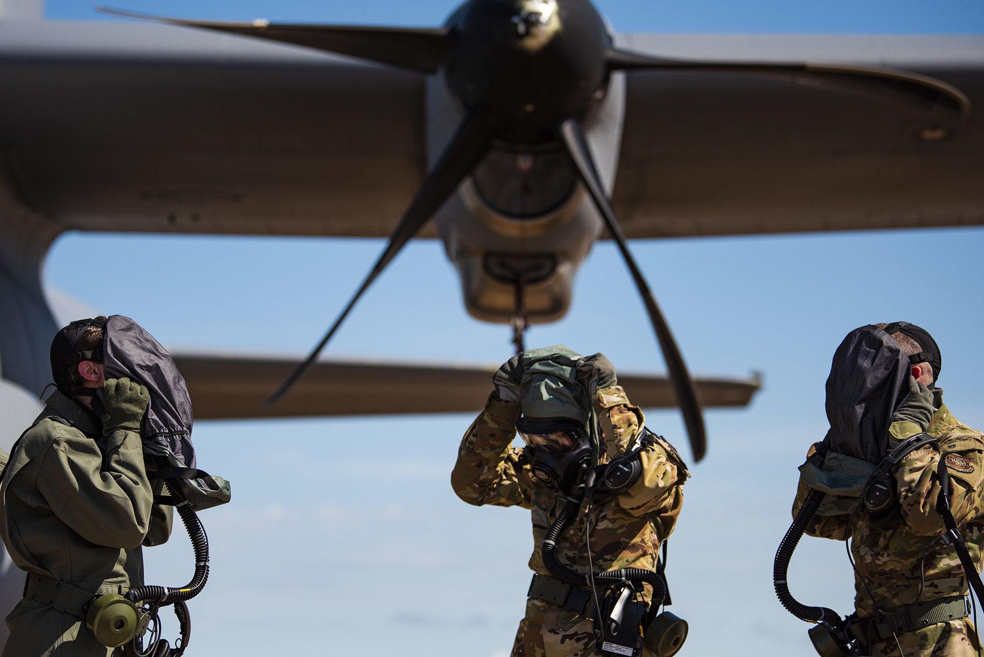 First Lt. Coltan Nading, 40th Airlift Squadron pilot, left, Capt. Miranda Mila, 40th AS pilot, center, and Senior Airman Noah Isom, 39th AS loadmaster, remove their gas masks next to a C-130J Super Hercules at Dyess Air Force Base, Texas, June 2, 2021. The aircrew demonstrated the operability of the new Uniform Integrated Protective Ensemble Air 2 Piece Under Garment chemical protective suit during simulated preflight and ground egress procedures. (Airman 1st Class Colin Hollowell/Air Force)