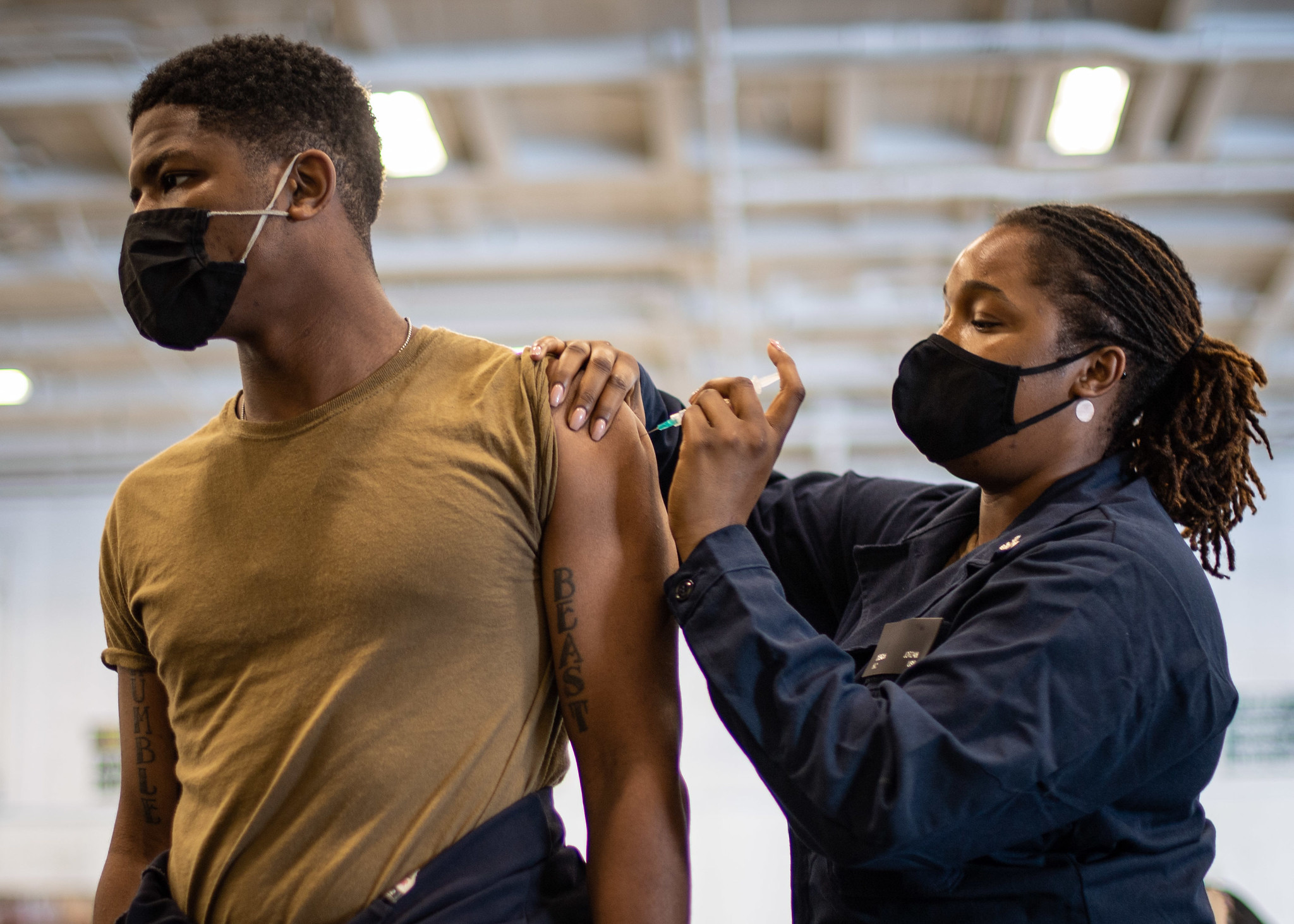 Hospital Corpsman 2nd Class Desirra Jordan administers a flu shot to Aviation Maintenance Administrationman 2nd Class Logan Ray in the hangar bay of the aircraft carrier USS Theodore Roosevelt (CVN 71), Oct. 15, 2020. (MC2 Zachary Wheeler/Navy)