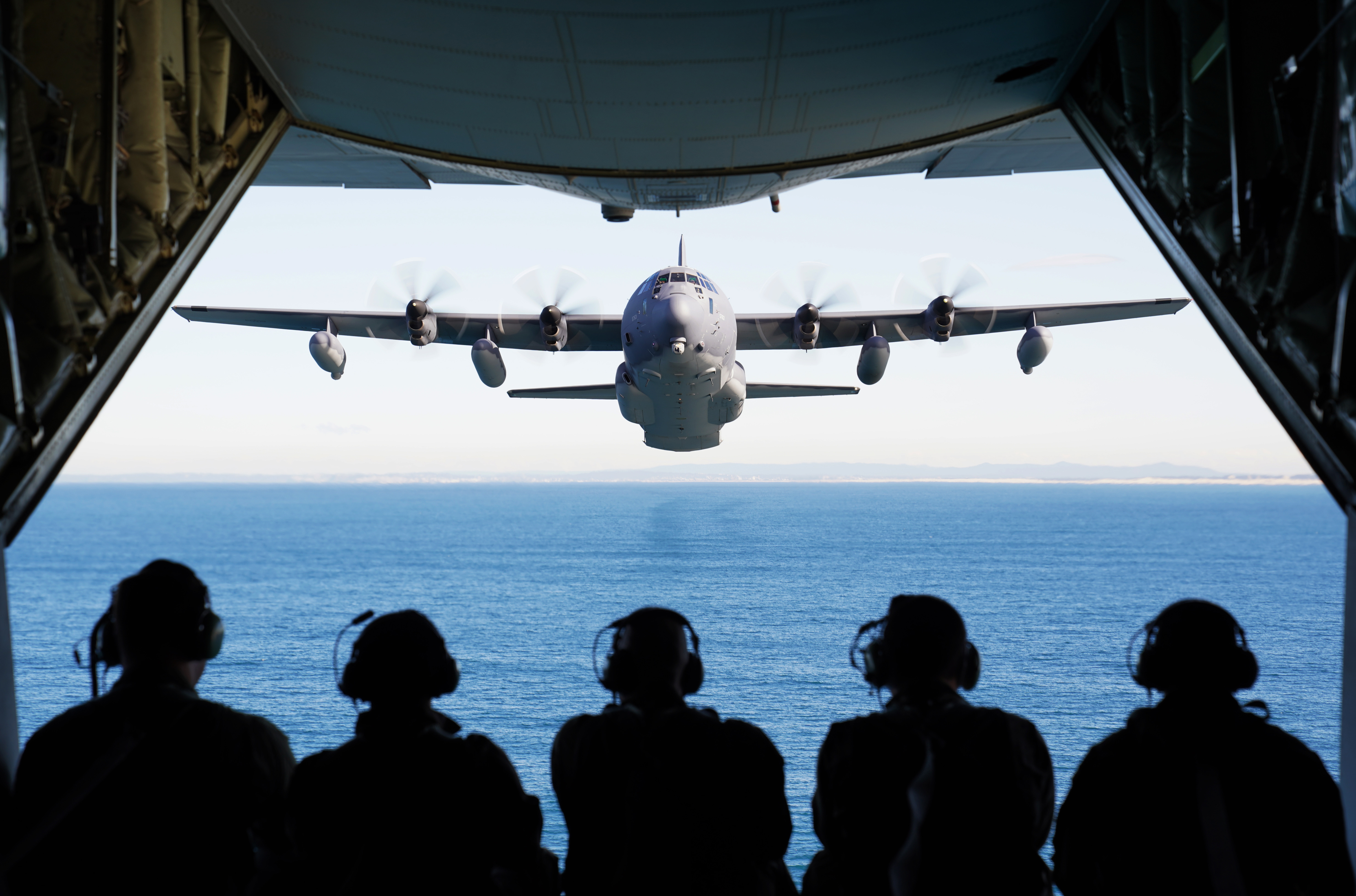 U.S. and Royal Australian Air Force airmen observe an MC-130J Air Commando II flying in formation off the coast of New South Wales, Australia, during exercise Teak Action 21 July 3. (1st Lt. Joshua Thompson/Air Force)