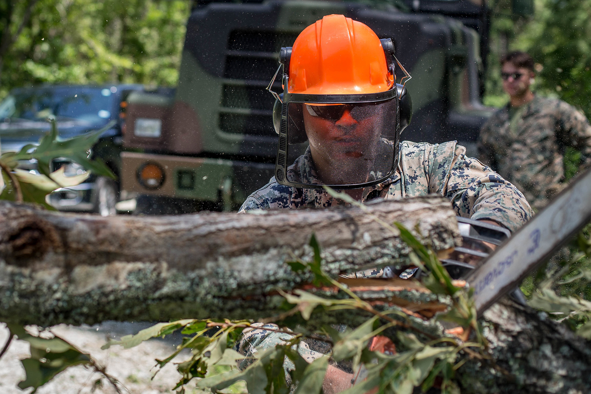 Cpl. William Butler uses a chainsaw to clear debris on a training area road at Marine Corps Air Station New River, N.C., Aug. 4, 2020, after Hurricane Isaias in order to resume normal operations. (Lance Cpl. Scott Jenkins/Marine Corps)