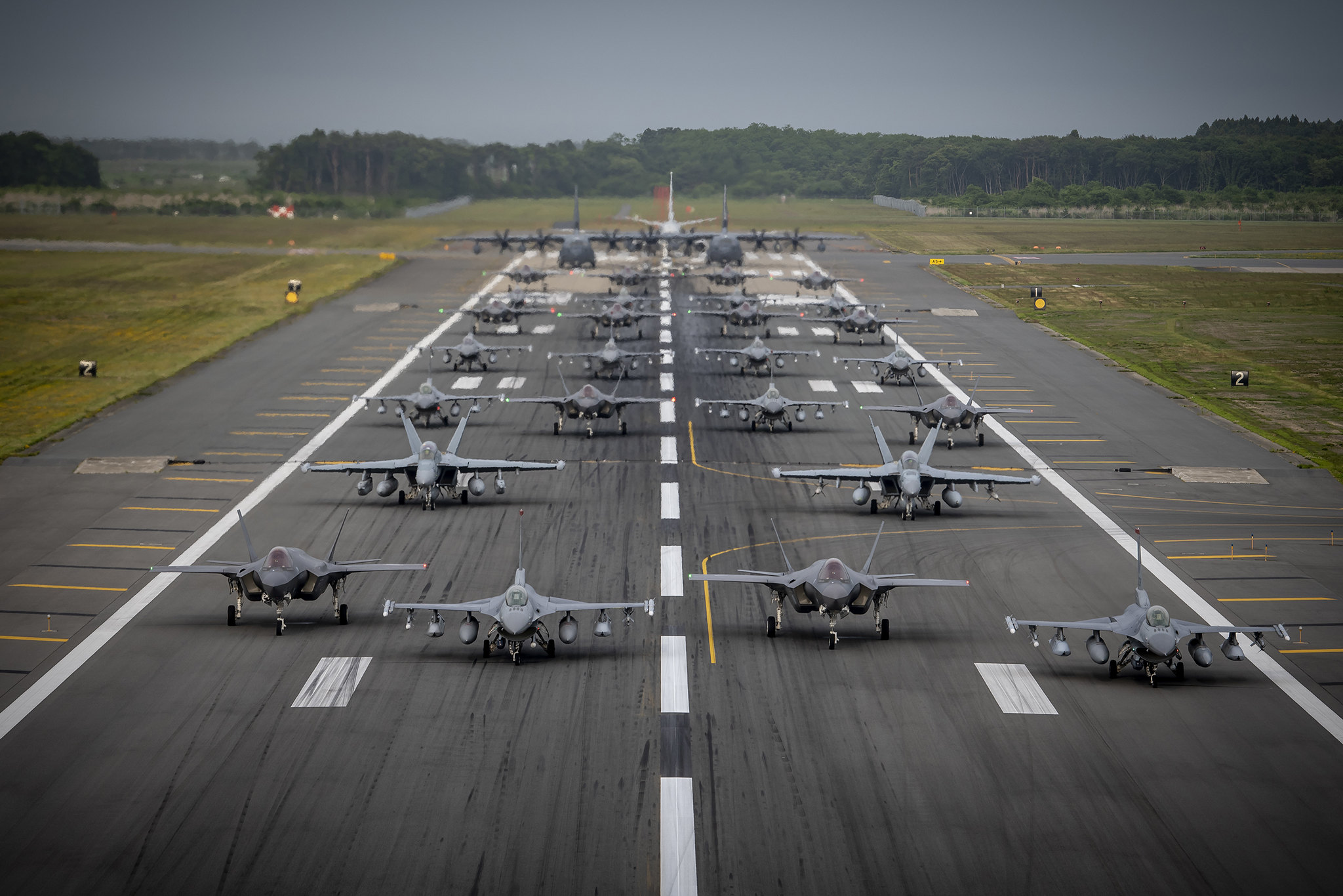 Twelve U.S. Air Force F-16CM Fighting Falcons, 12 Koku-Jieitai F-35A Lightning II Joint Strike Fighters, two U.S. Navy EA-18G Growlers, a USN C-12 Huron, two USAF MC-130J Commando II aircraft, and a USN P-8 Poseidon participate in an “Elephant Walk” at Misawa Air Base, Japan, June 22, 2020. It was Misawa Air Base’s first time hosting a bilateral and joint Elephant Walk. (Airman 1st Class China M. Shock/Air Force)