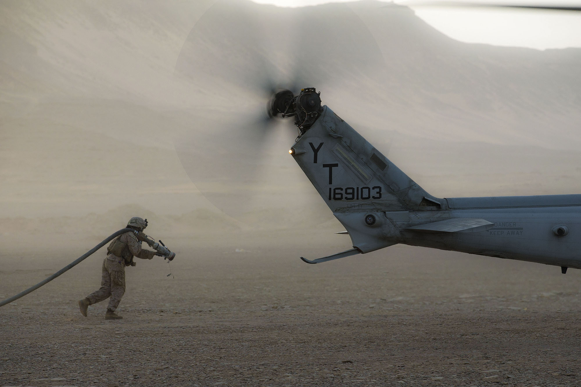 Marine Corps Cpl. Selina Lopez carries a fuel hose to a UH-1Y Venom at a forward arming and refueling point during a theater amphibious combat rehearsal (TACR) in Tabuk, Kingdom of Saudi Arabia, March 9, 2021. (Lance Cpl. Brendan Mullin/Marine Corps)