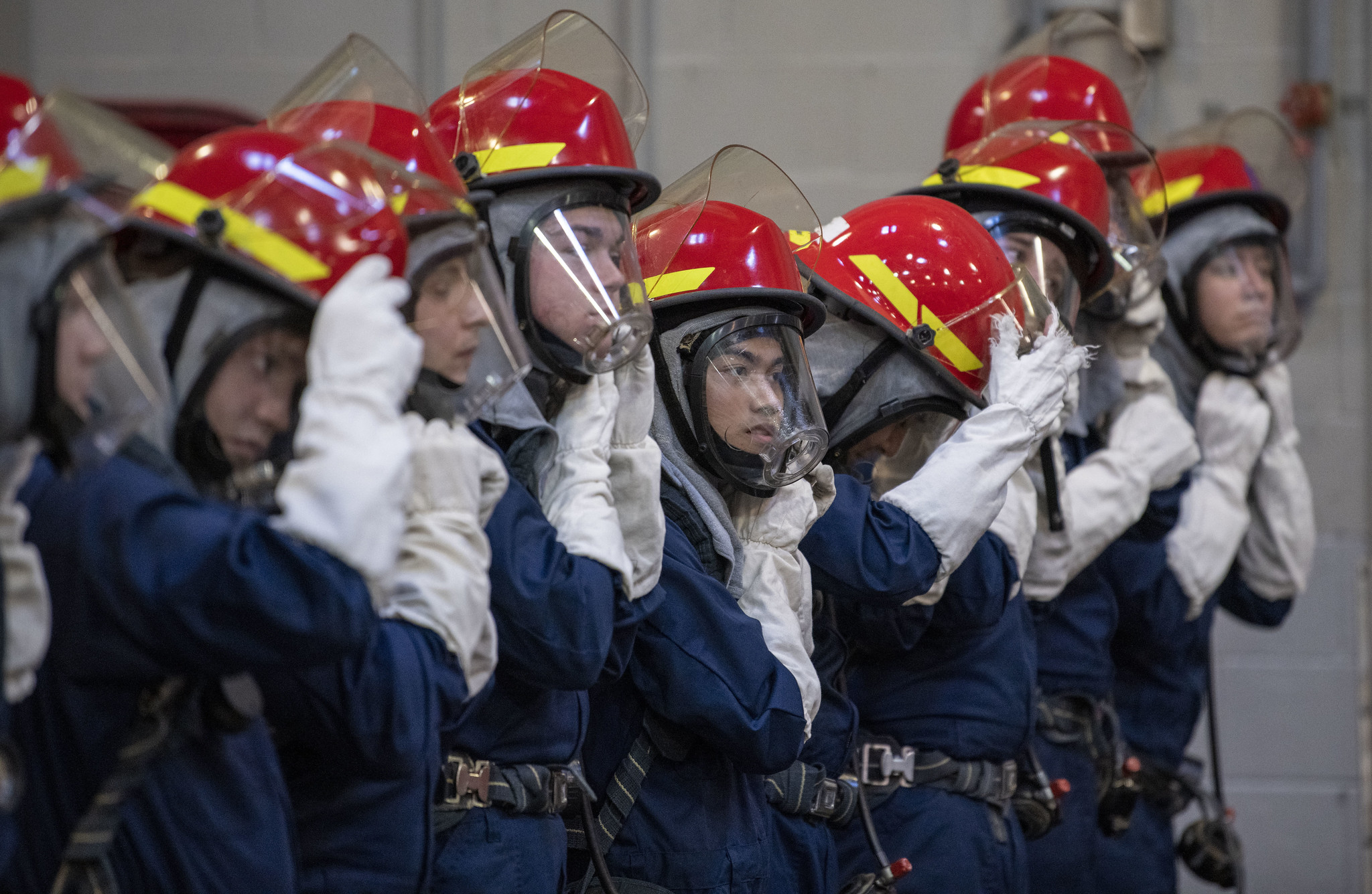 Recruits secure their head gear during firefighting training inside the USS Chief Firefighter Trainer at Recruit Training Command on Jan. 12, 2021, at Great Lakes, Ill. (Seaman Maurice Brown/Navy)