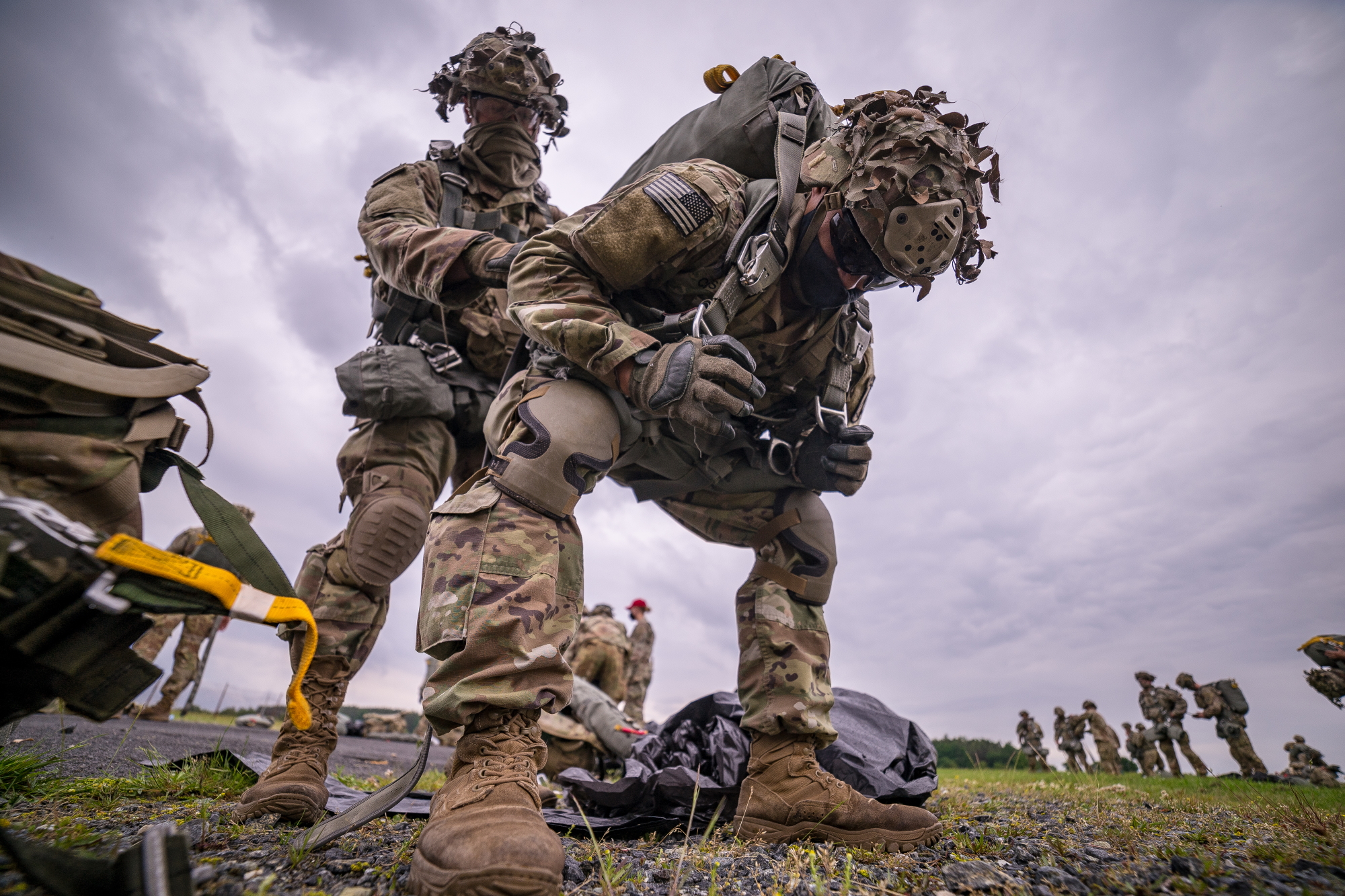 U.S. Army paratroopers from the 1st Squadron (Airborne), 91st Cavalry Regiment, 173rd Airborne Brigade, help each other don parachutes in preparation for an airborne jump at Grafenwoehr Army Air Field, Germany, June 10, 2020. (Staff Sgt. Christopher Stewart/Army)