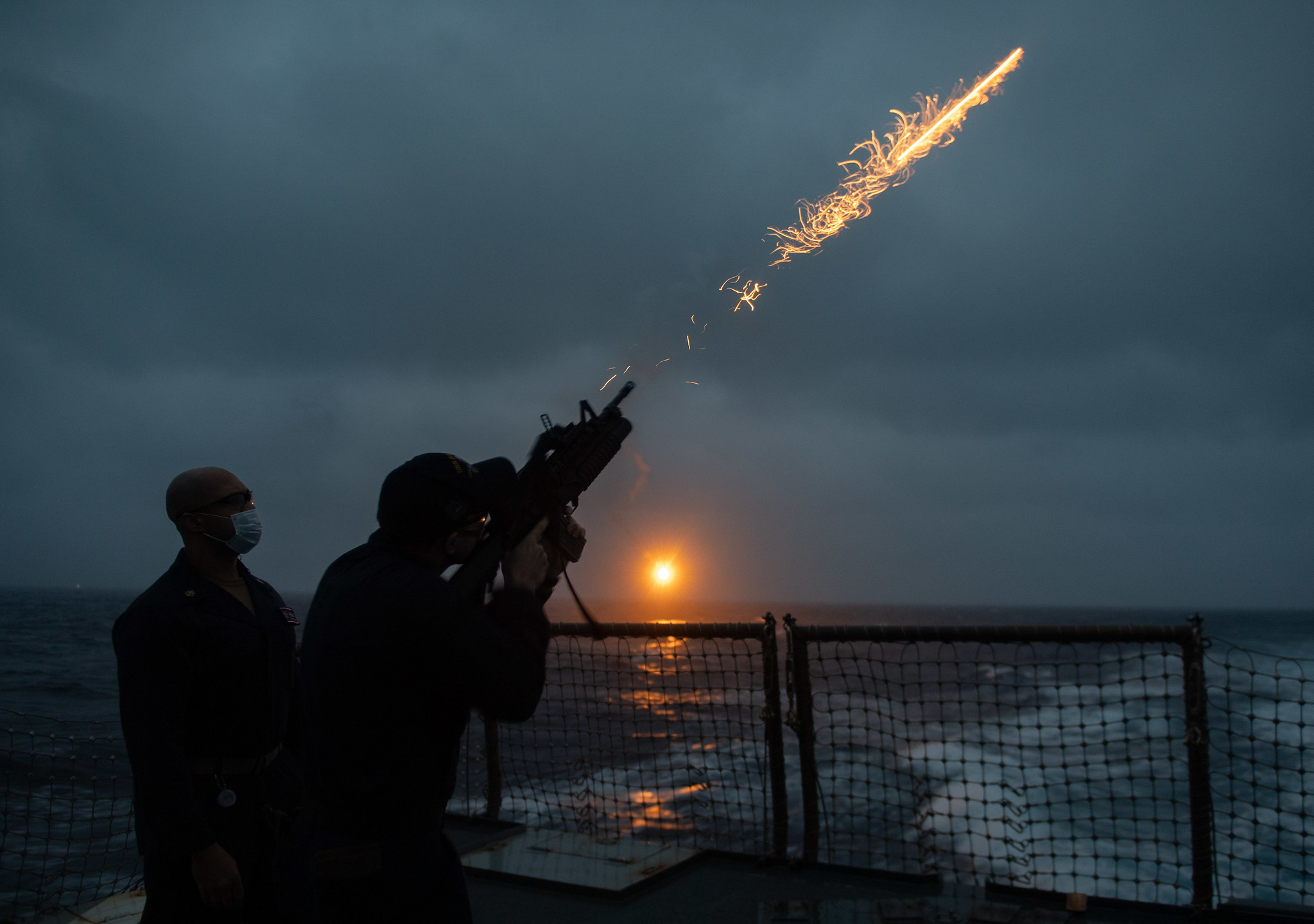 Chief Gunner’s Mate Ricardo Stewart, left, watches as Gunner’s Mate 3rd Class Cullen McArdle fires a flare during a flare exercise in the Philippine Sea aboard the Arleigh Burke-class guided-missile destroyer USS Barry (DDG 52). (Mass Communications Specialist Seaman Molly M. Crawford/Navy)