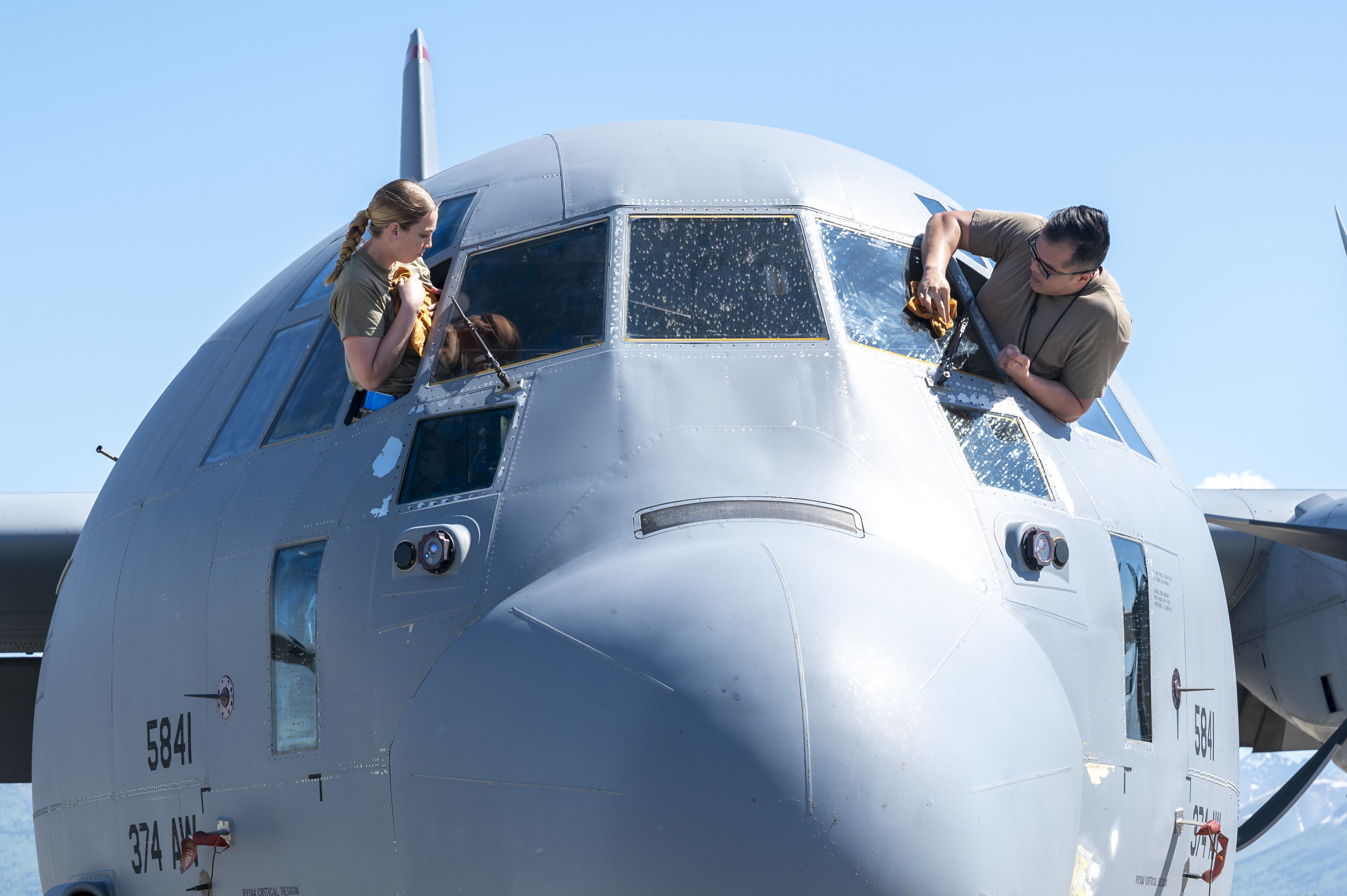 Airman 1st Class Sarah Miller and Senior Airman Austin Dihn, 374th Aircraft Maintenance Squadron, clean the windows of a C-130J Super Hercules during Red Flag-Alaska 21-2 at Joint Base Elmendorf-Richardson, Alaska, June 14. (Airman 1st Class Mario Calabro/Air Force)
