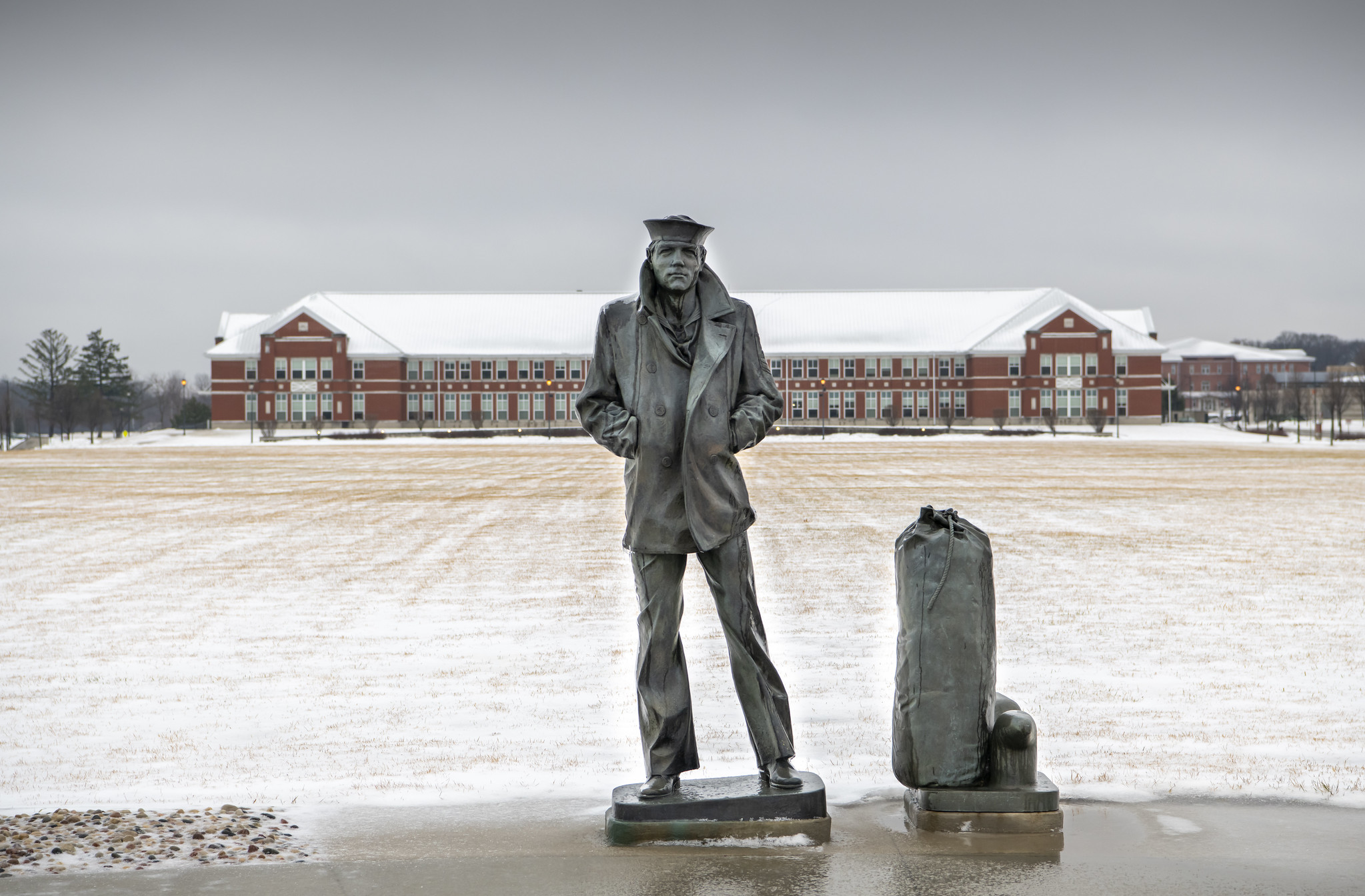 The statue of the Lone Sailor stands on the snow-covered grounds of Recruit Training Command at Great Lakes, Ill., on Dec. 30, 2020. (MC1 Spencer Fling/Navy)