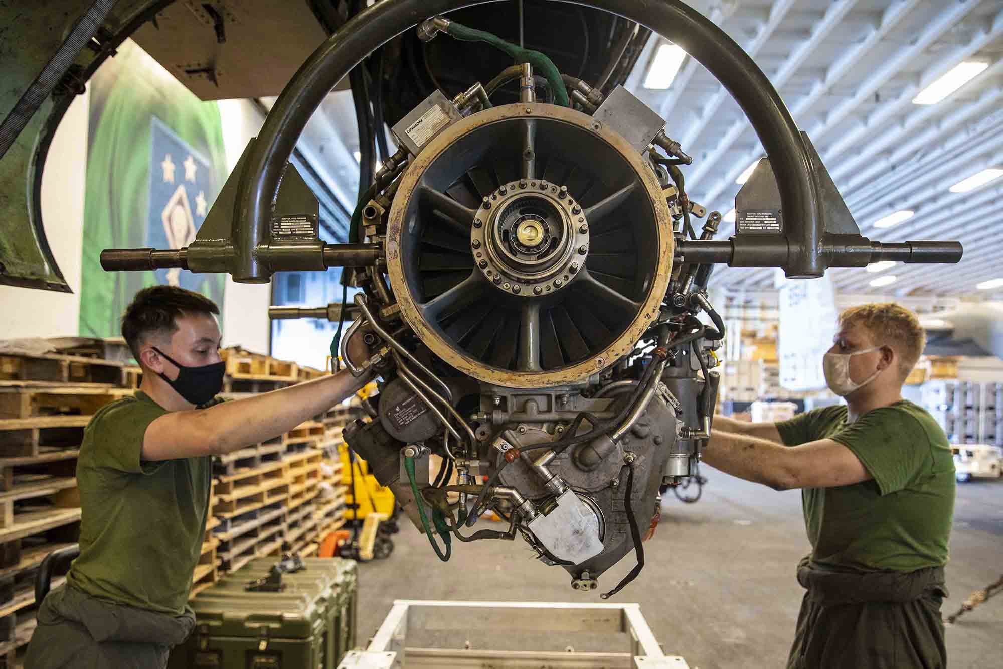 Marine Corps Sgt. William Easter, right, and Lance Cpl. Nathaniel Hinkle remove an engine from an Osprey aboard the amphibious assault ship USS Makin Island (LHD 8) on Jan. 19, 2021, in the Indian Ocean. (MC3 Aaron Sperle/Navy)