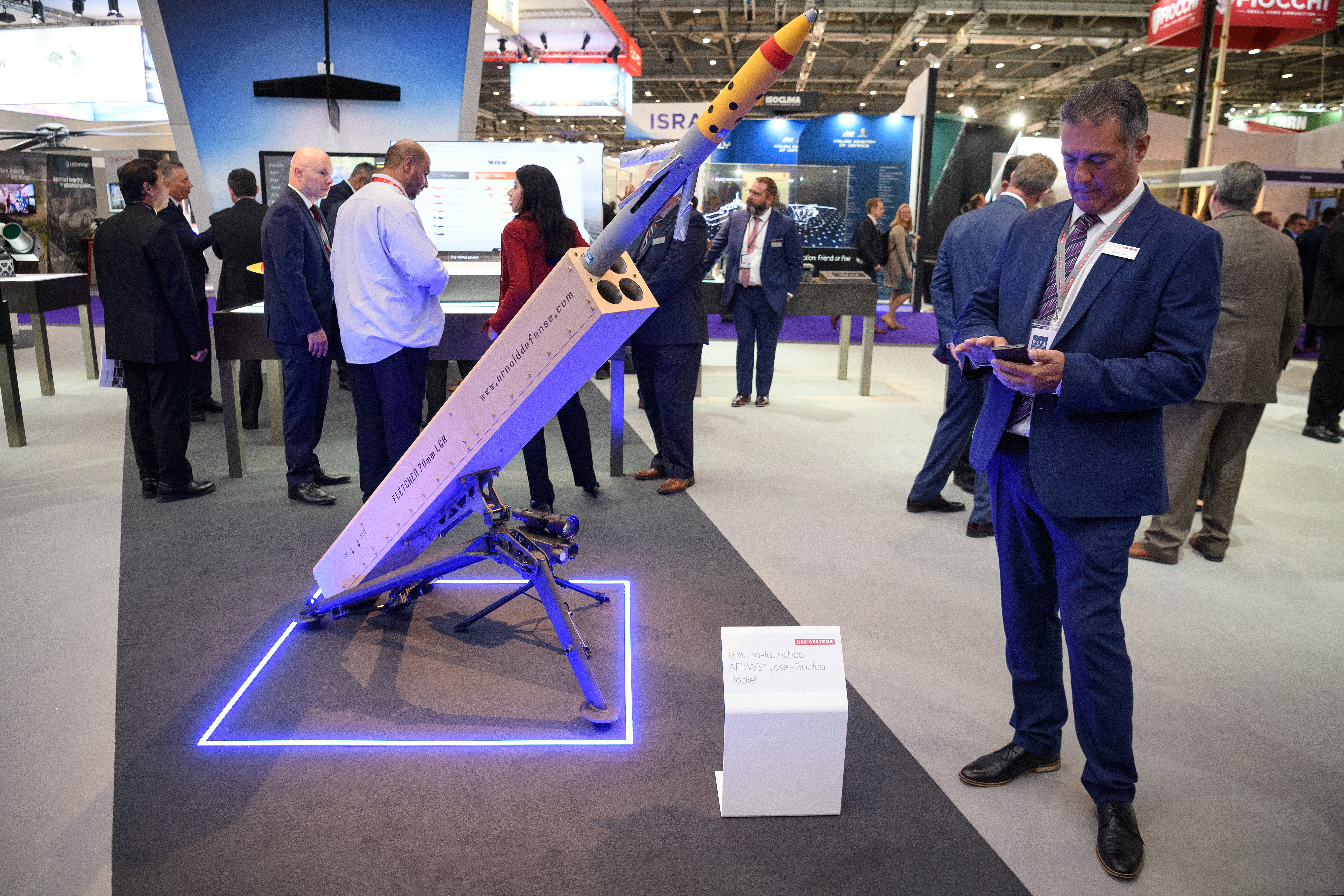 A man checks his phone as he stands next to the ground-based APKWS laser-guided rocket by BAE Systems on the second day of DSEI. (Leon Neal/Getty Images)