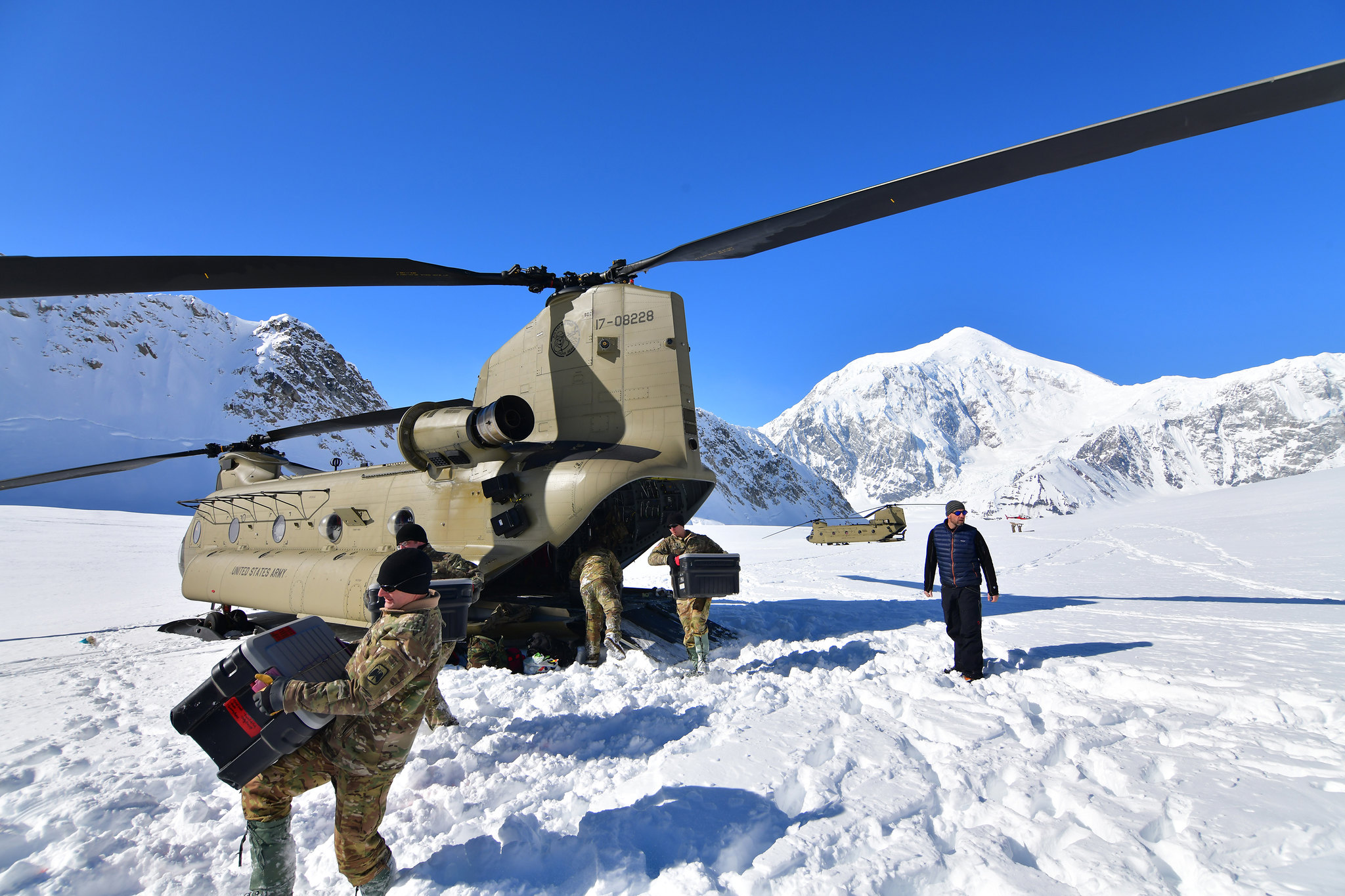 Soldiers from B Company, 1st Battalion, 52nd Aviation Regiment unload equipment and supplies from a pair of CH-47F Chinook helicopters on Kahiltna Glacier, April 22, 2021. Aviators from the unit, also known as the Sugar Bears, traveled from Fort Wainwright to help the National Park Service get the necessary equipment and supplies in place for the base camp at the 7,200-foot level of Kahiltna Glacier for the 2021 climbing season on Denali, the tallest mountain in North America. (John Pennell/Army)