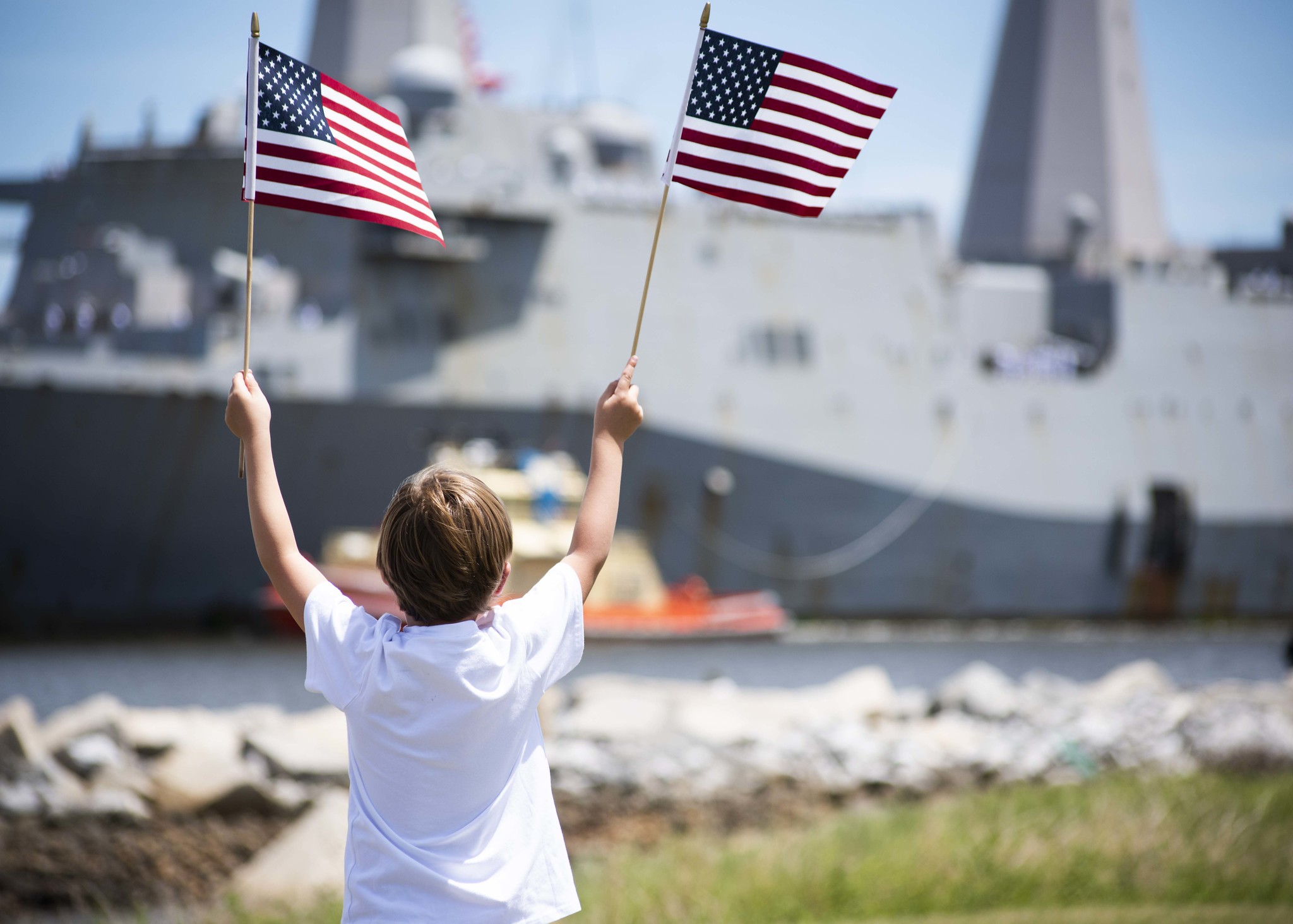 A family member waives American flags as the San Antonio-class amphibious transport dock ship USS New York (LPD 21) arrives at Naval Station Mayport in Florida on July 28, 2020. (MC1 Brian G. Reynolds/Navy)
