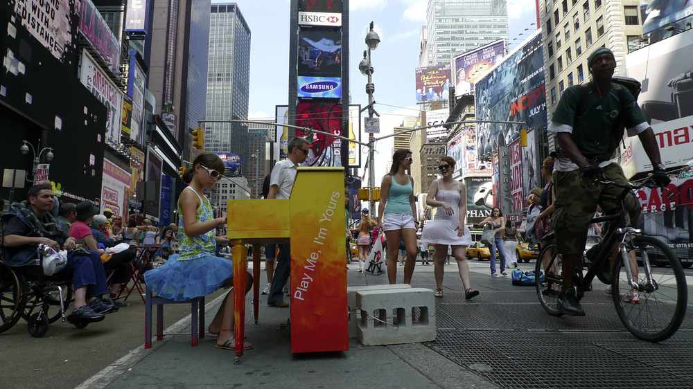 A girl plays one of many pianos installed on the streets of New York as part of the Play Me, I'm Yours scheme