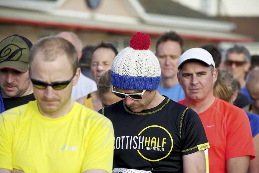 Runners bow their heads during a minute's silence at FB Fields before Sunday's half-marathon