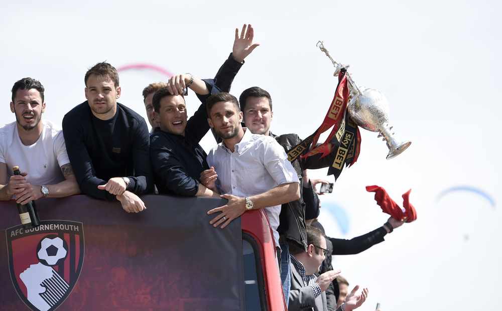 Jeseyman Brett Pitman (left) celebrates with team mates during the open top bus parade along Bournemouth beach front yesterday. Bournemouth were promoted to the Premier League after becoming Sky Bet Championship Champions on Saturday