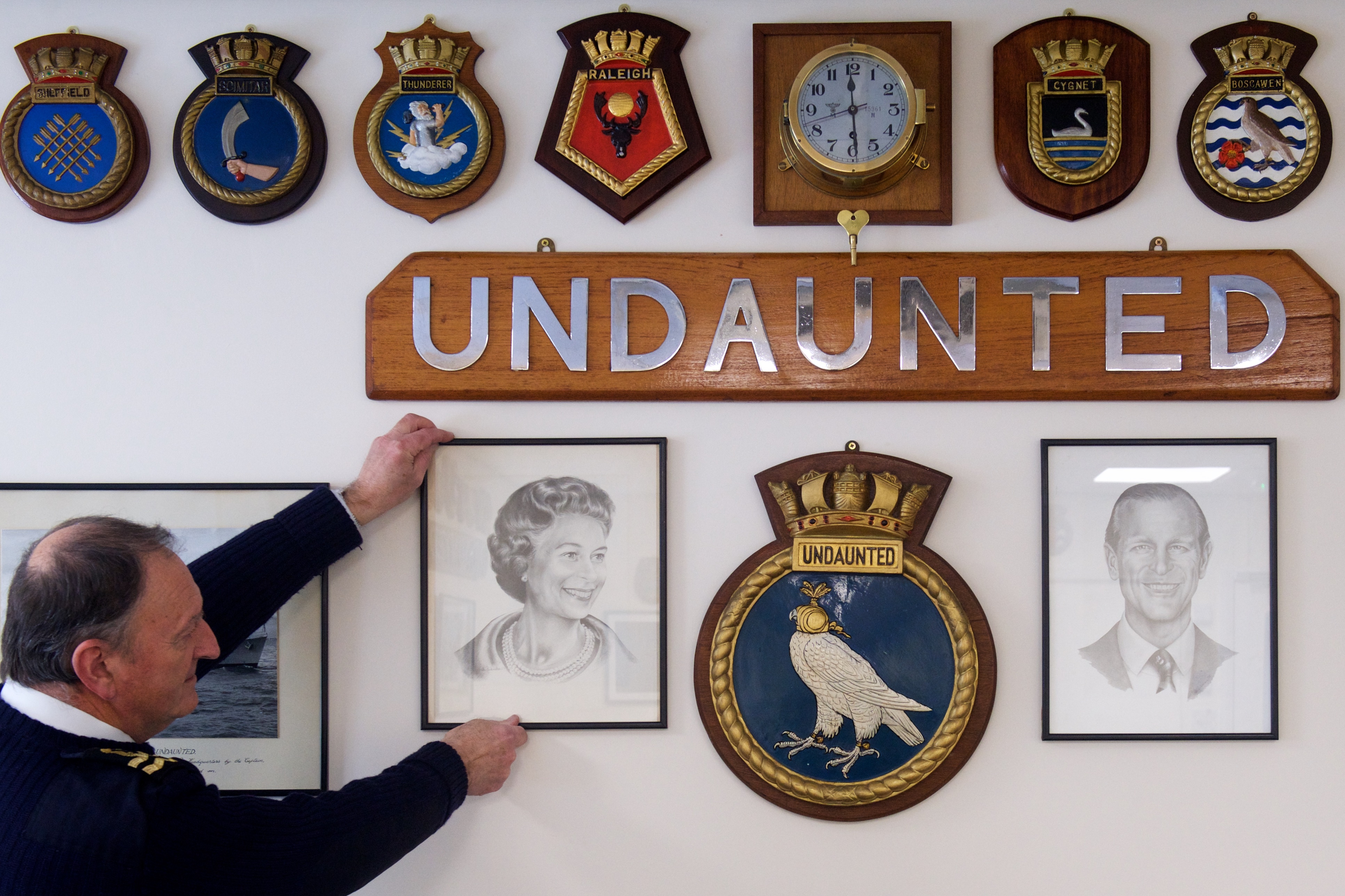 Lt André Bonjour, Commanding Officer of the Jersey Sea Cadets straightens a portrait of the Queen in the wardroom of their new headquarters at the former police station in Rouge Bouillon in preparation for the official opening by the Governor on Monday 22 March. Picture: JON GUEGAN. (30581094)