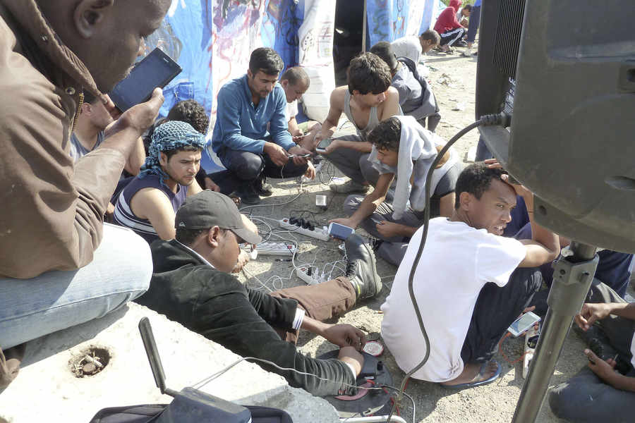 Occupants of the Calais 'jungle gather to charge their mobile phones