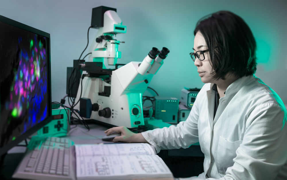 A microscopist works with fluorescent tissue samples, carrying out the latest research into cancer