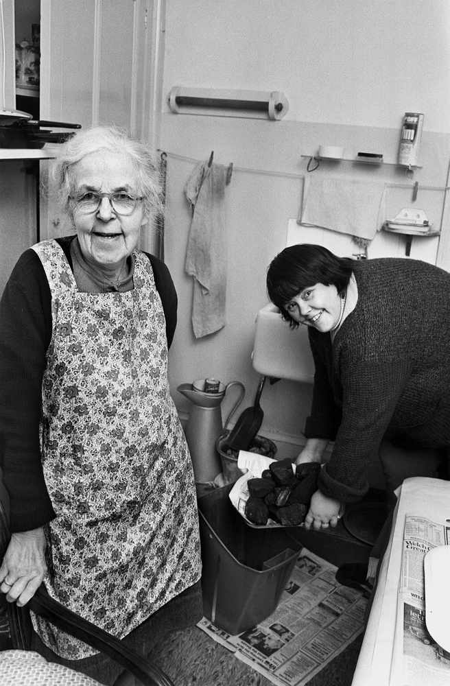 This picture from 1979 shows Mrs Le Gros, who was pleased with the help she was getting from Family Nursing home help. Mrs Pirouet, who is bringing in the coal.
