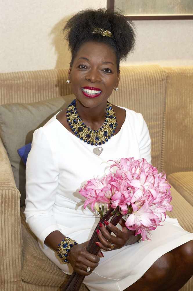 Floella Benjamin holding a bunch of Jersey Lillies