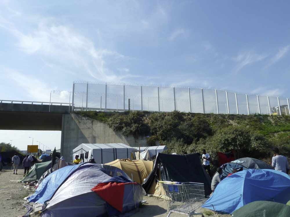 Tents erected below a high fence at the camp