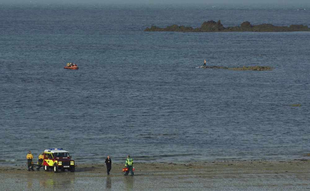Police in the inshore rescue craft approach Darren McCormick (circled) as he stands on a rock at La Mare