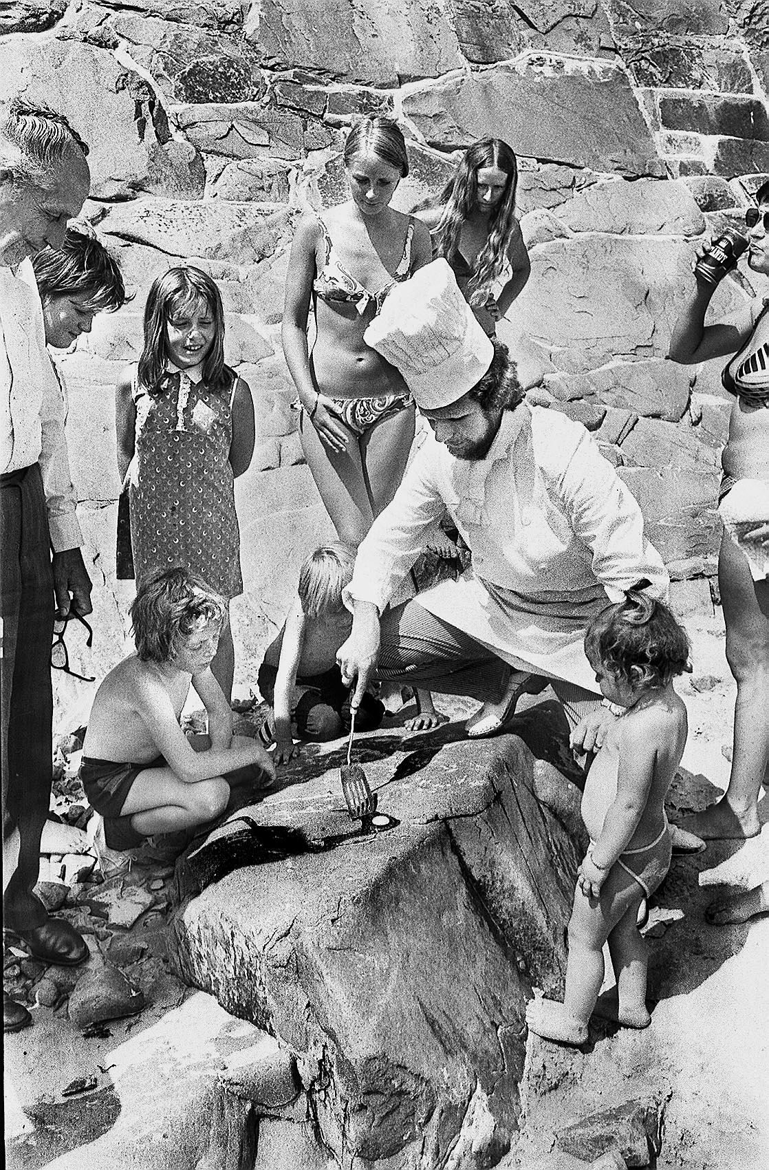 CHILDREN AND OTHER SPECTATORS WATCH AS A CHEF TRIES HIS HAND AT FRYING AN EGG ON THE BEACH DURING THE LONG HOT SUMMER OF 1976 (29017039)