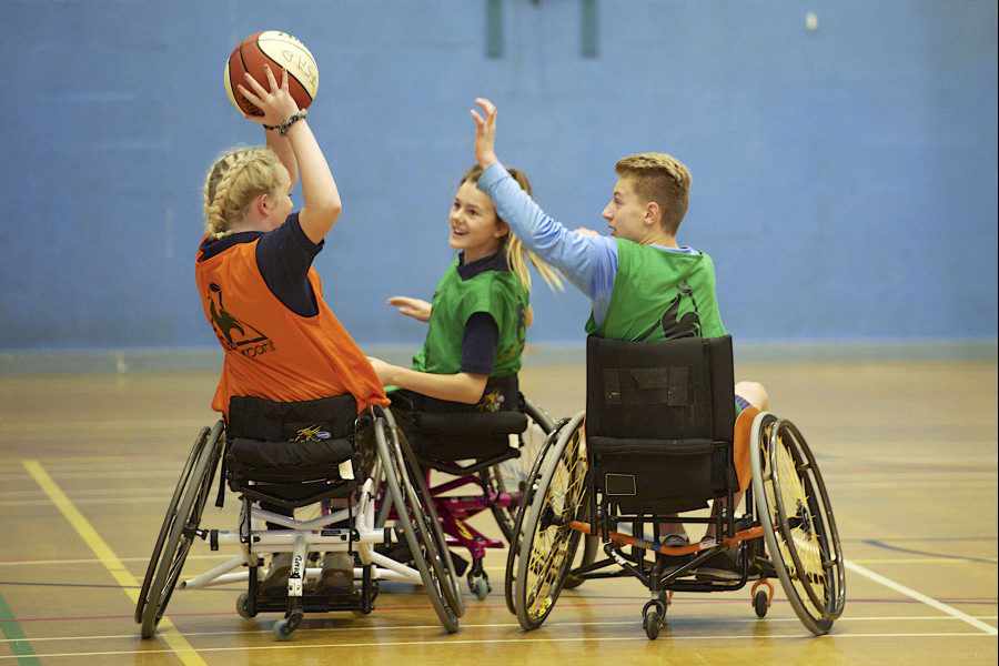 Les Quennevais students Jasmyn Botterill, Avena Bouteloup and Tom Webster enjoying wheelchair basketball as part of the Schools' Outreach Programme