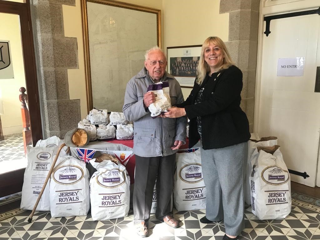 Mr Brian Pipon receiving a bag of Jersey Royals from Constable Deidre Mezbourian. The parish gave away the bags to Occupation veterans on Friday to celebrate Liberation Day. Picture: Parish of St Lawrence (30810076)