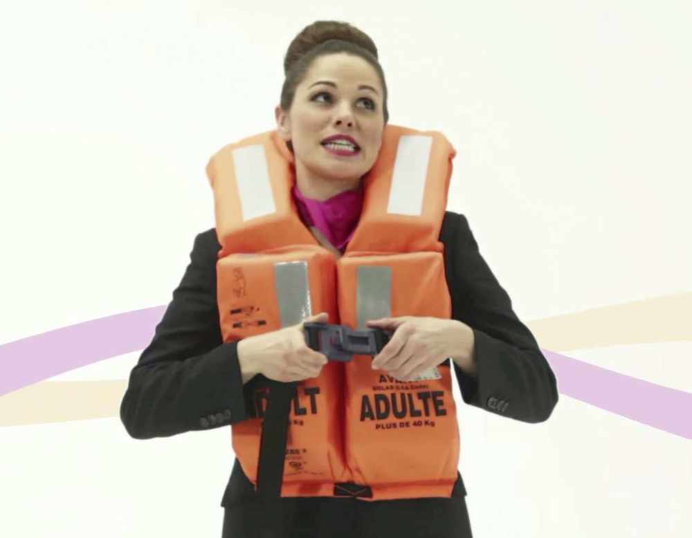 The sassy stewardess demonstrates the life jacket