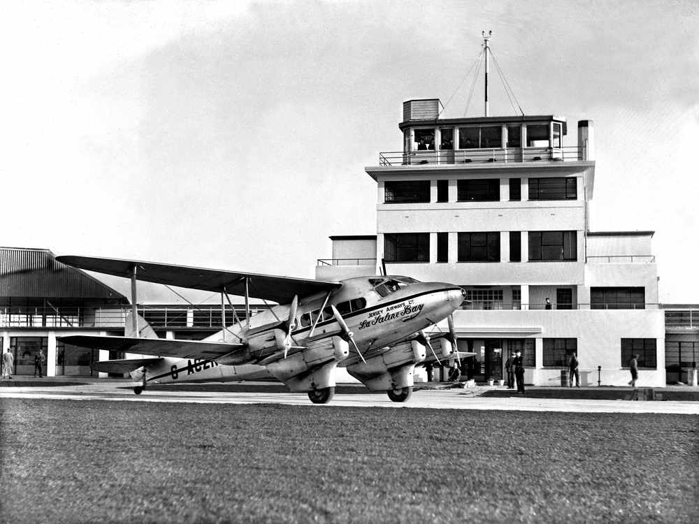 A Jersey Airways plane, La Saline Bay, stands in front of the airport control tower building at Jersey's new airport in January 1937. Although the airport was not officially opened until two months later, in March 1937, this aircraft had landed for an engine overhaul before continuing her flight to Heston.