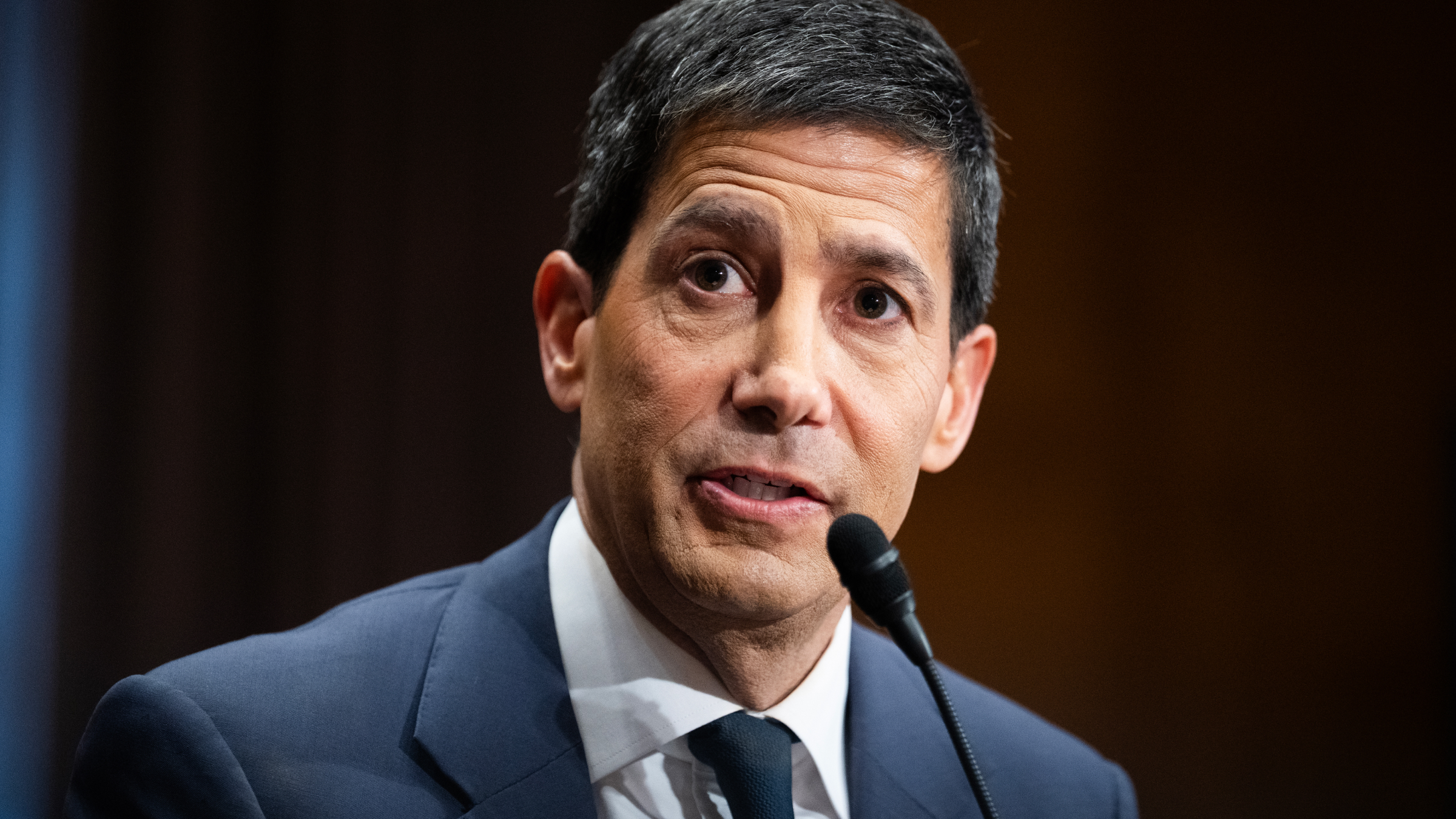 Kevin Warsh talking into a microphone.