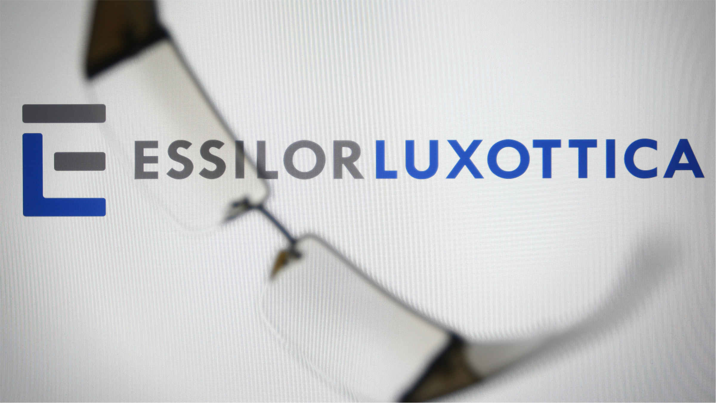The EssilorLuxottica logo on a pc screen in the background.
