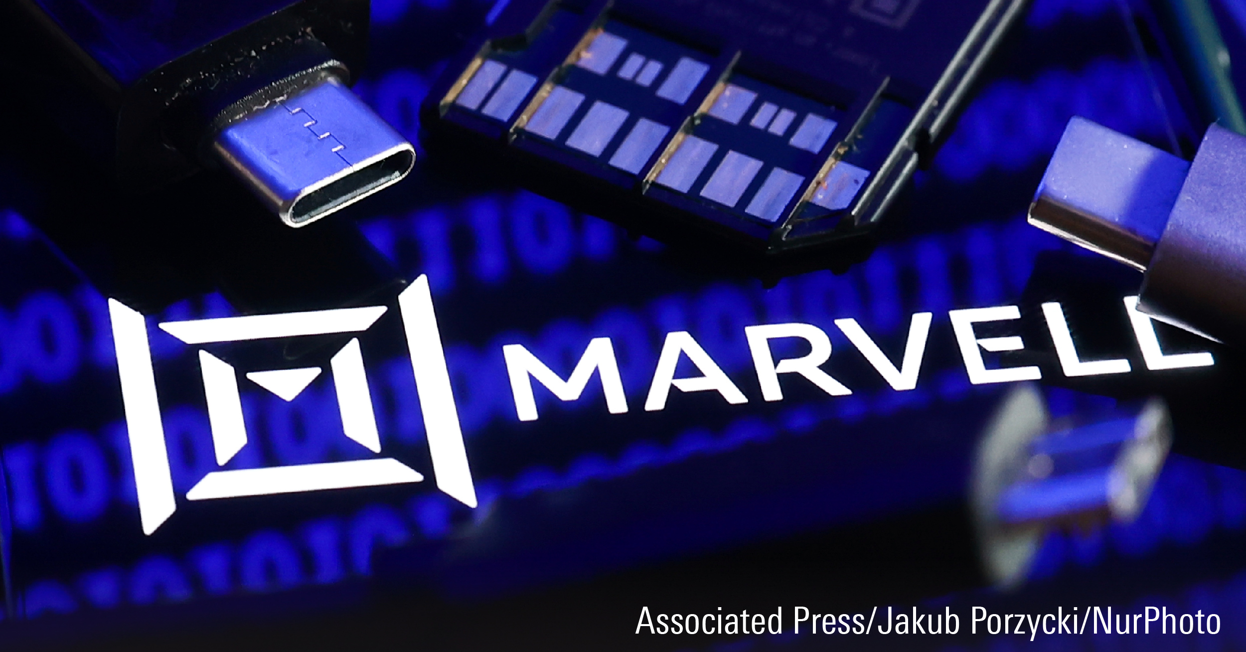 Marvell logo displayed on a phone screen with a binary code reflected on it, a laptop keyboard, a memory card, an adapter and cables are seen in this illustration photo.