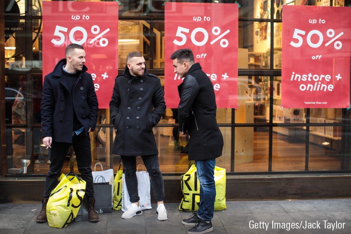A photo of three holiday shoppers with bags of clothing.