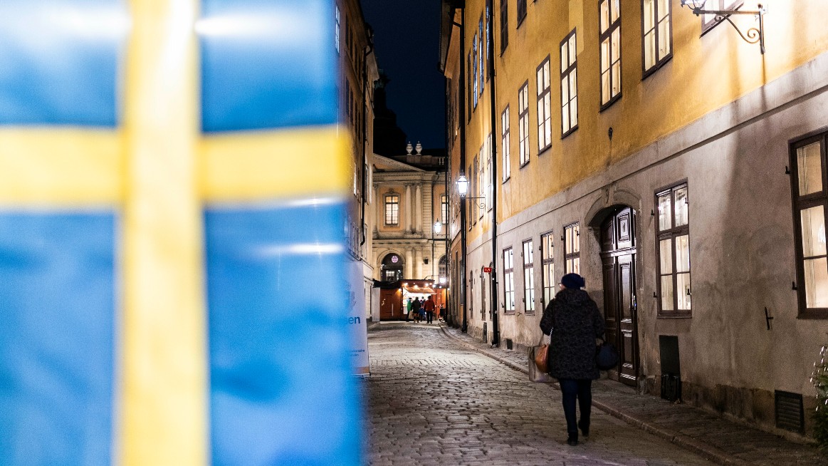 Svensk flagga med person som g&aring;r i gamla stan