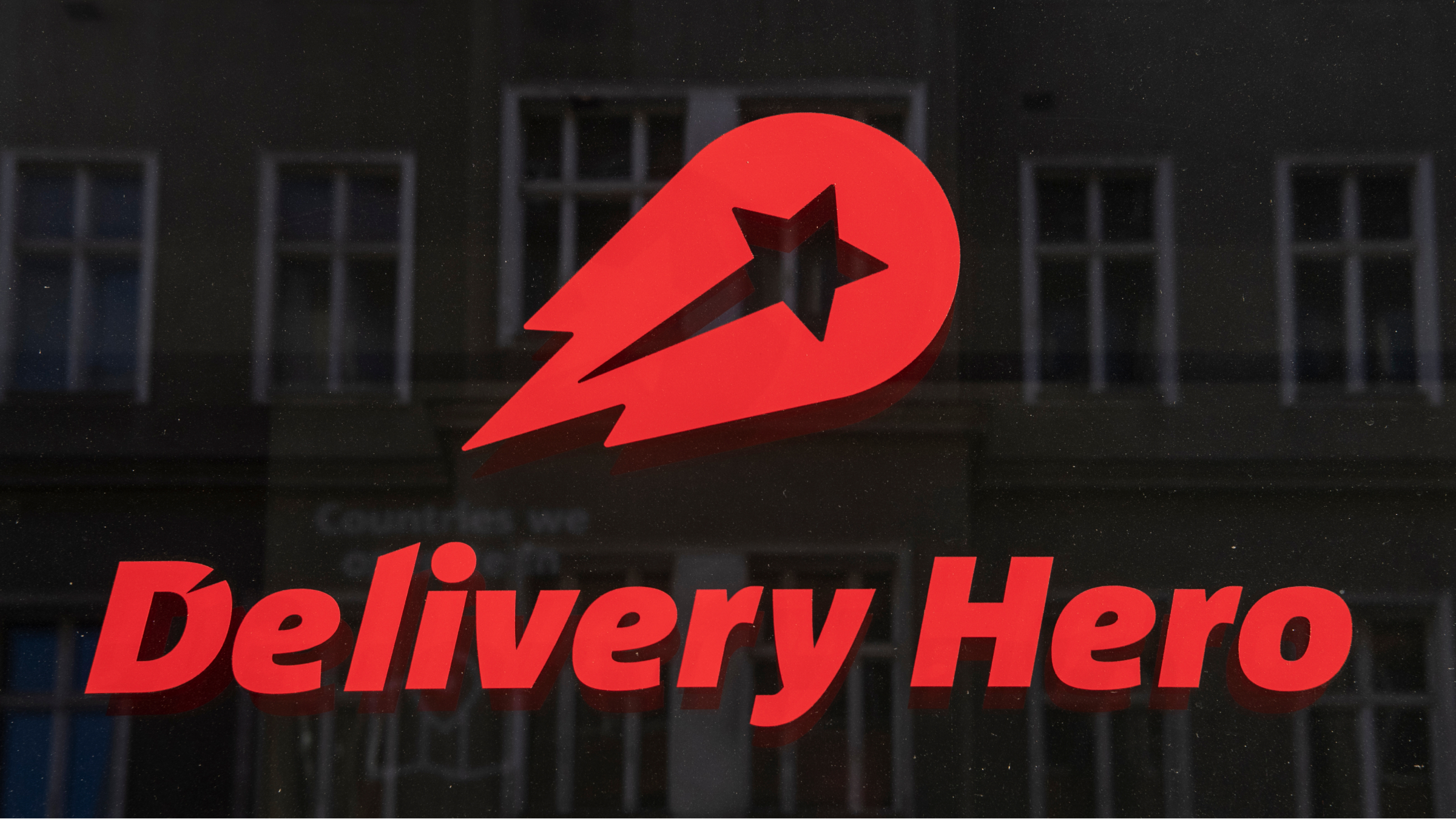 Das Logo und der Schriftzug des Essenslieferdienstes Delivery Hero sind in einem Fenster am Hauptsitz des Unternehmens zu sehen.