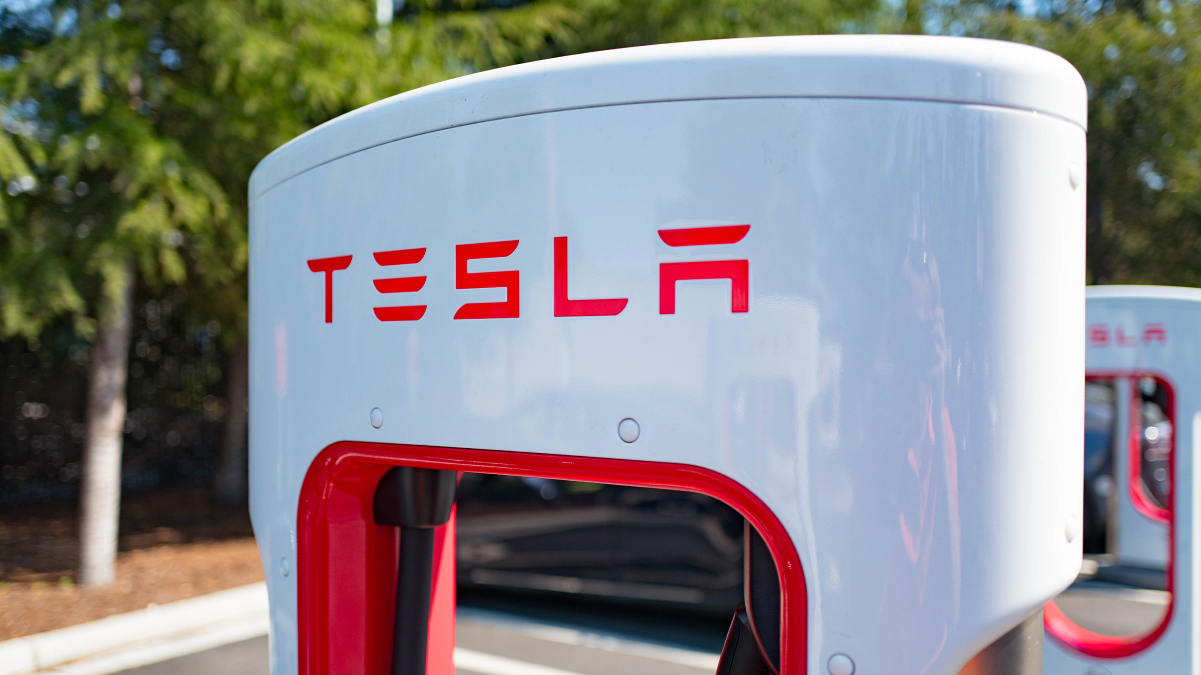 Charger with Tesla logo at a Supercharger rapid battery charging station.
