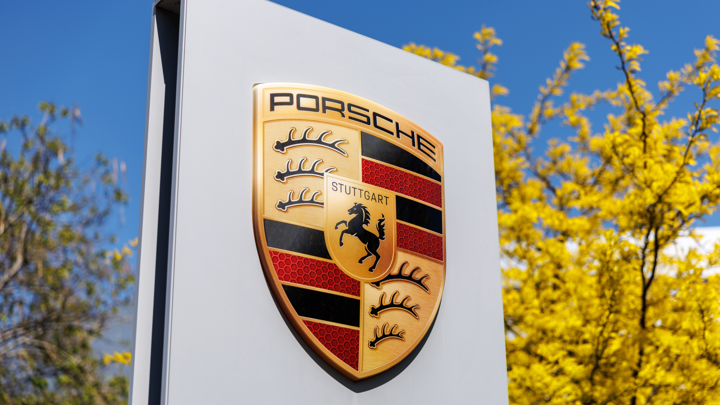 The brand logo and the lettering of the car manufacturer Porsche can be seen at a branch of the company.