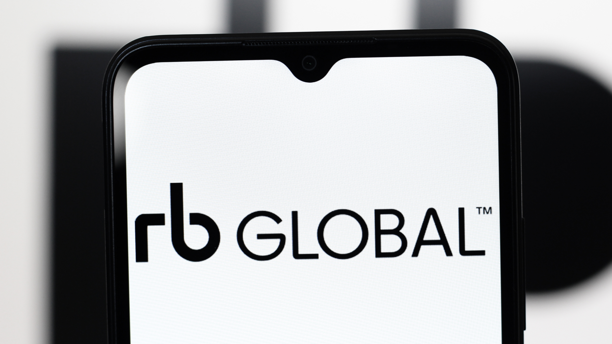 The RB Global Inc. logo is seen displayed on a smartphone screen.