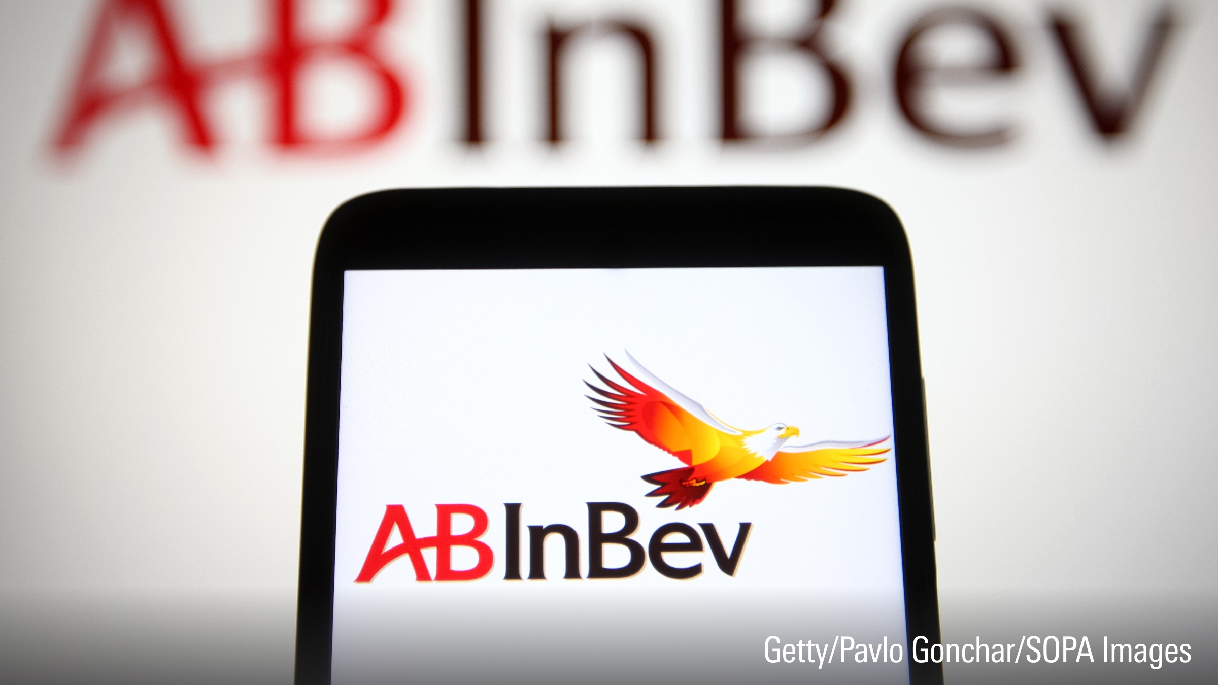 In this photo illustration an AB InBev (Anheuser-Busch InBev) logo is seen on a smartphone and a pc screen.