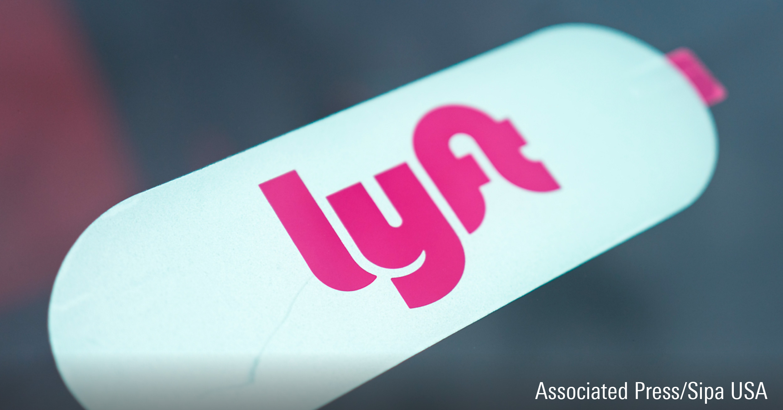 Close-up of logo for ride sharing and crowdsourced taxi service Lyft on a Lyft vehicle.