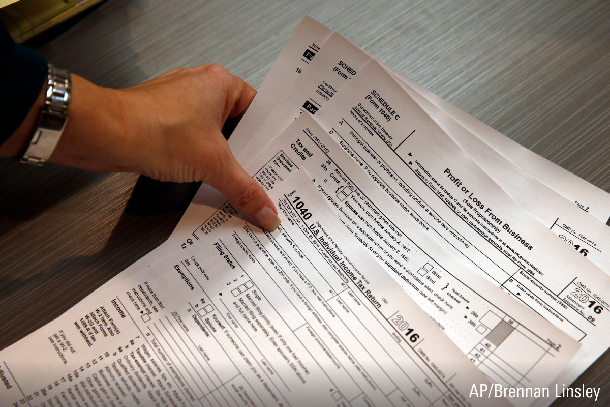 Person placing a few tax documents from the Internal Revenue of Service on a table