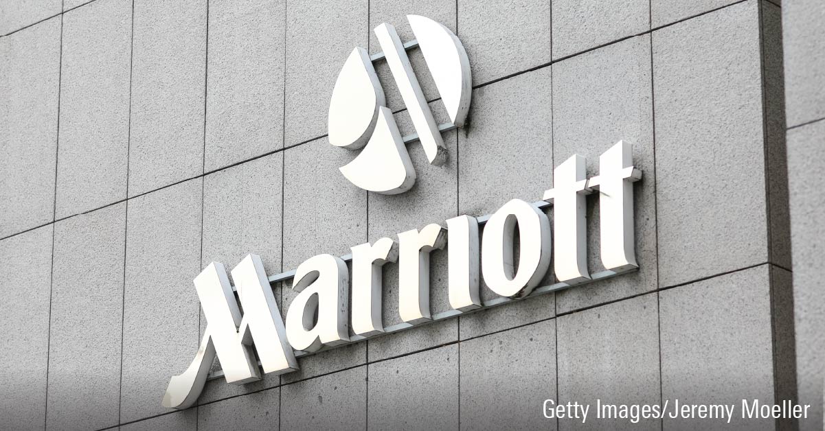 A white Marriott hotel logo sign superimposed on a grey-brick building.