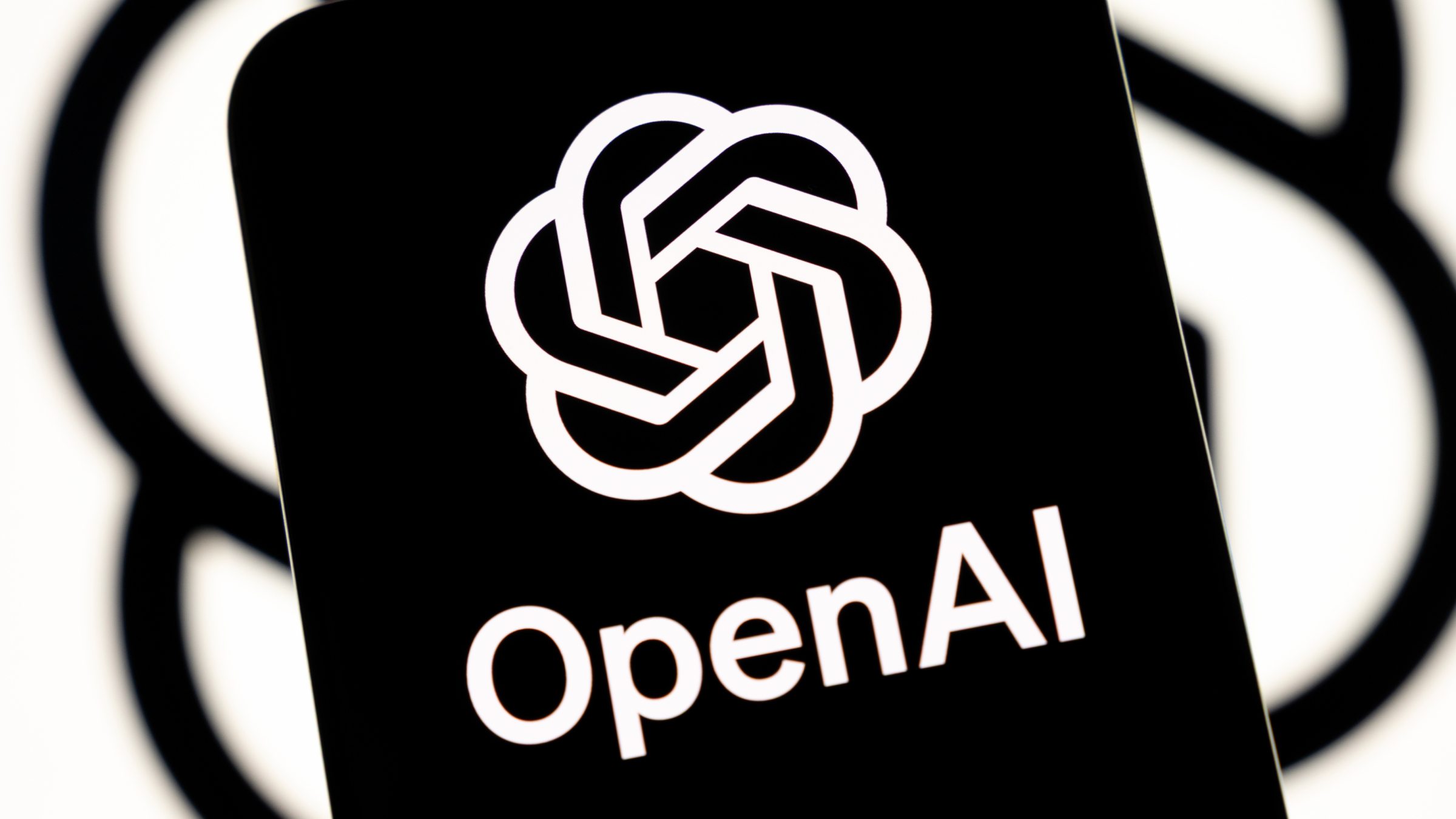 The OpenAI logo appears on a smartphone screen.