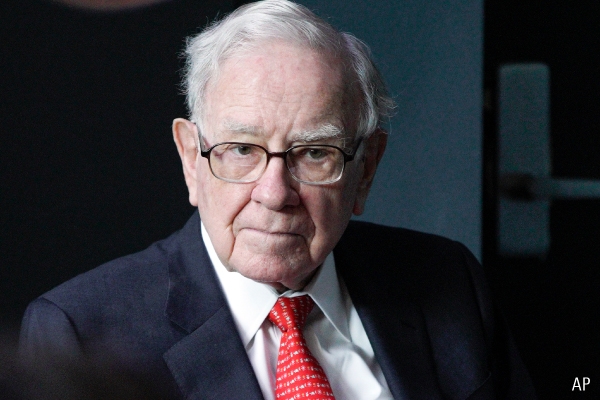 Warren Buffett, CEO and chair of Berkshire Hathaway, wears a dark suit and red tie and looks thoughtful.