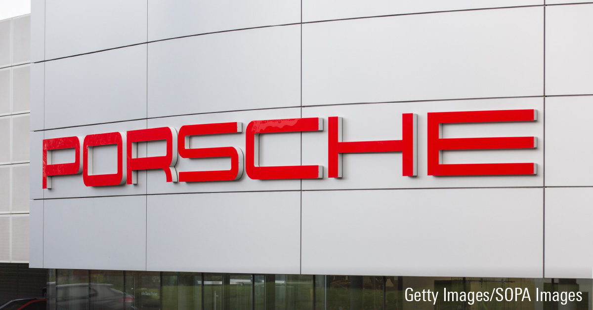 Red Porsche logo sign on Porsche center showroom building.