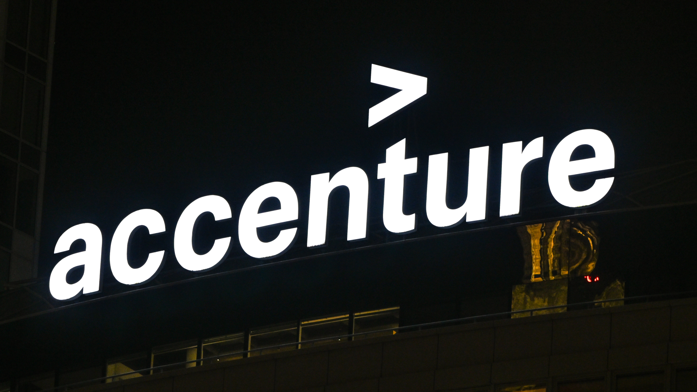 The illuminated white logo of Accenture.