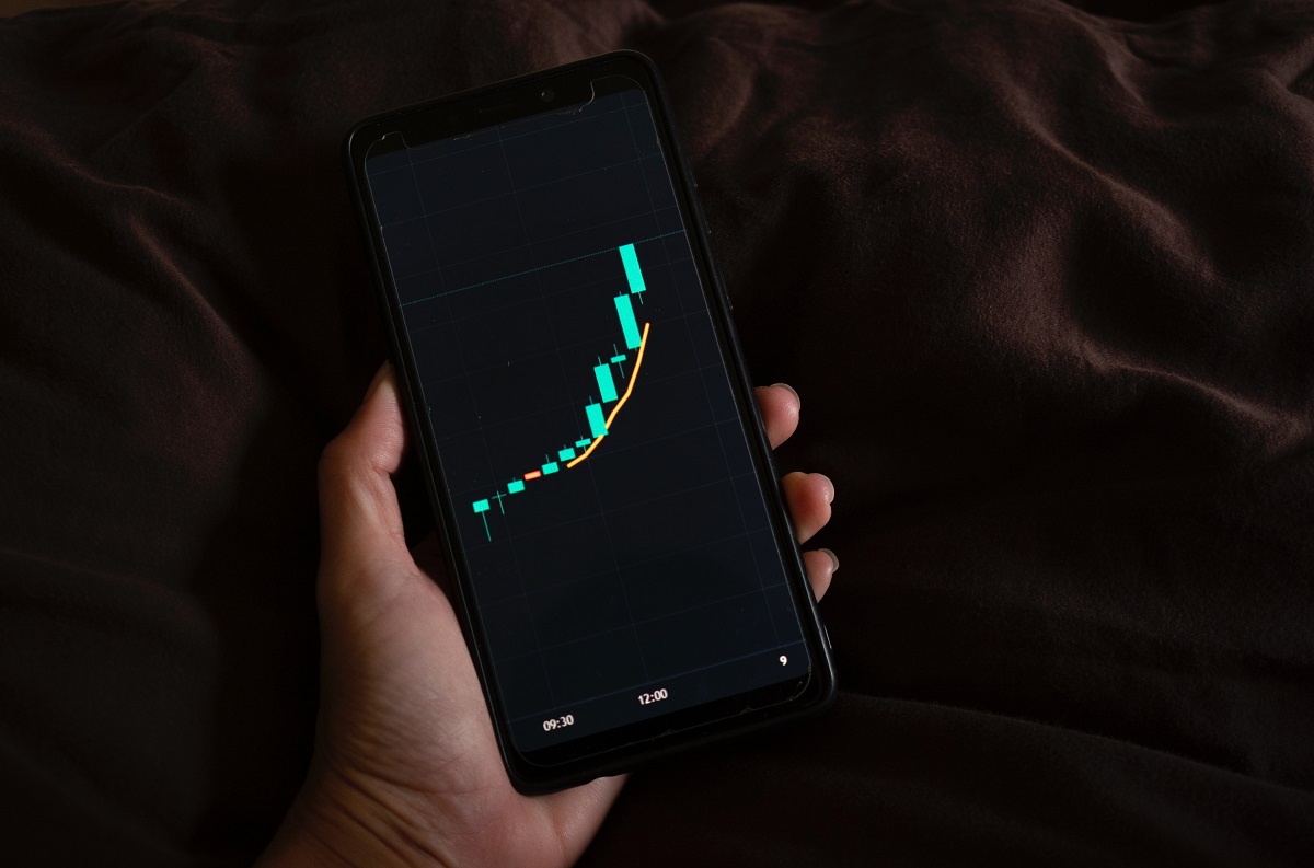 Person holding a smartphone and using a trading app