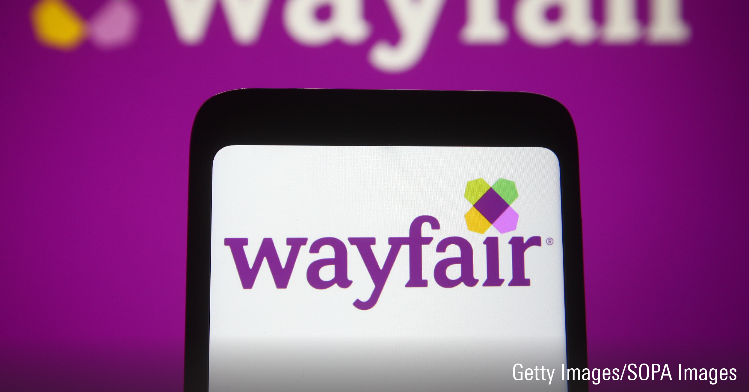 In this photo illustration, the Wayfair logo is seen displayed on a smartphone and a pc screen.