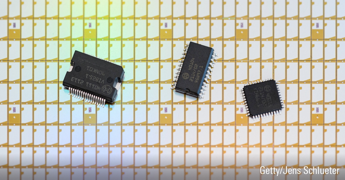 Drie halfgeleiderchips op een rij bovenop een vel met elektronische chips.